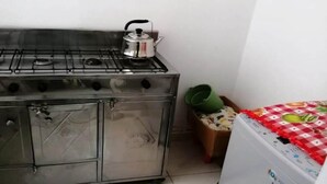 Ett kök med en spis i rostfritt stål, en vattenkokare och en tvättmaskin.