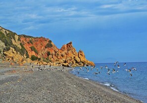 A pebbled beach with rocky cliffs and birds flying over the water. - Sea View Apartment in the center of Oued Laou 4208 (Oued Laou)