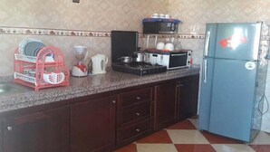 A kitchen with a microwave, stove, and refrigerator. There is a dish rack and a coffee maker on the counter. - Sea View Apartment in the center of Oued Laou 4208 (Oued Laou)
