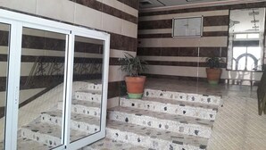 A hotel lobby with striped walls, a glass door entrance, and a staircase with potted plants. - Sea View Apartment in the center of Oued Laou 4208 (Oued Laou)