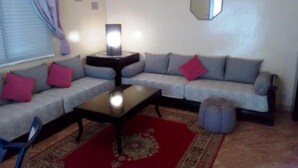 Un salon avec un canapé gris, une table basse, un tapis et un miroir au mur.