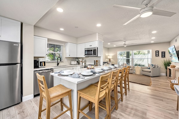 A modern kitchen with a central island, stainless steel appliances, and wooden chairs.