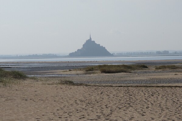 Een strand met een grote, piramidevormige structuur in de verte.