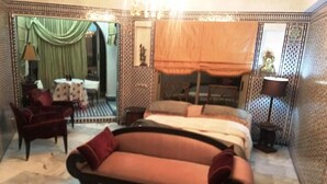 A bedroom with a bed, a sofa, a chair, and a table.