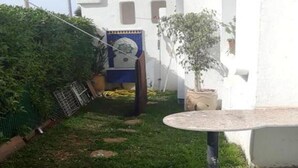 A small, enclosed outdoor area with a round table, a potted plant, and a blue tiled wall.