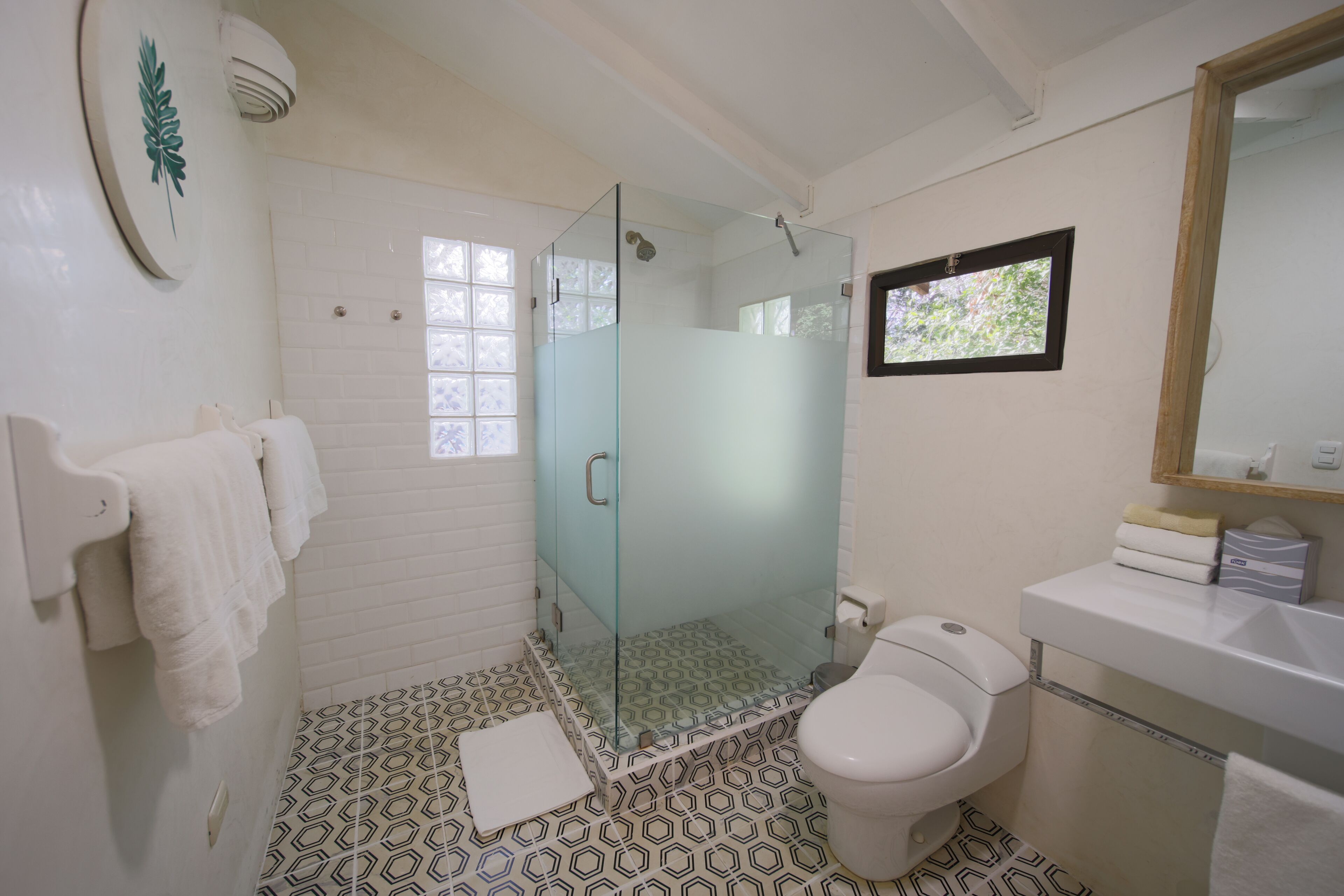 A bathroom with a glass-enclosed shower, a toilet, and a sink.