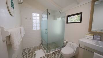 A bathroom with a glass-enclosed shower, a toilet, and a sink.