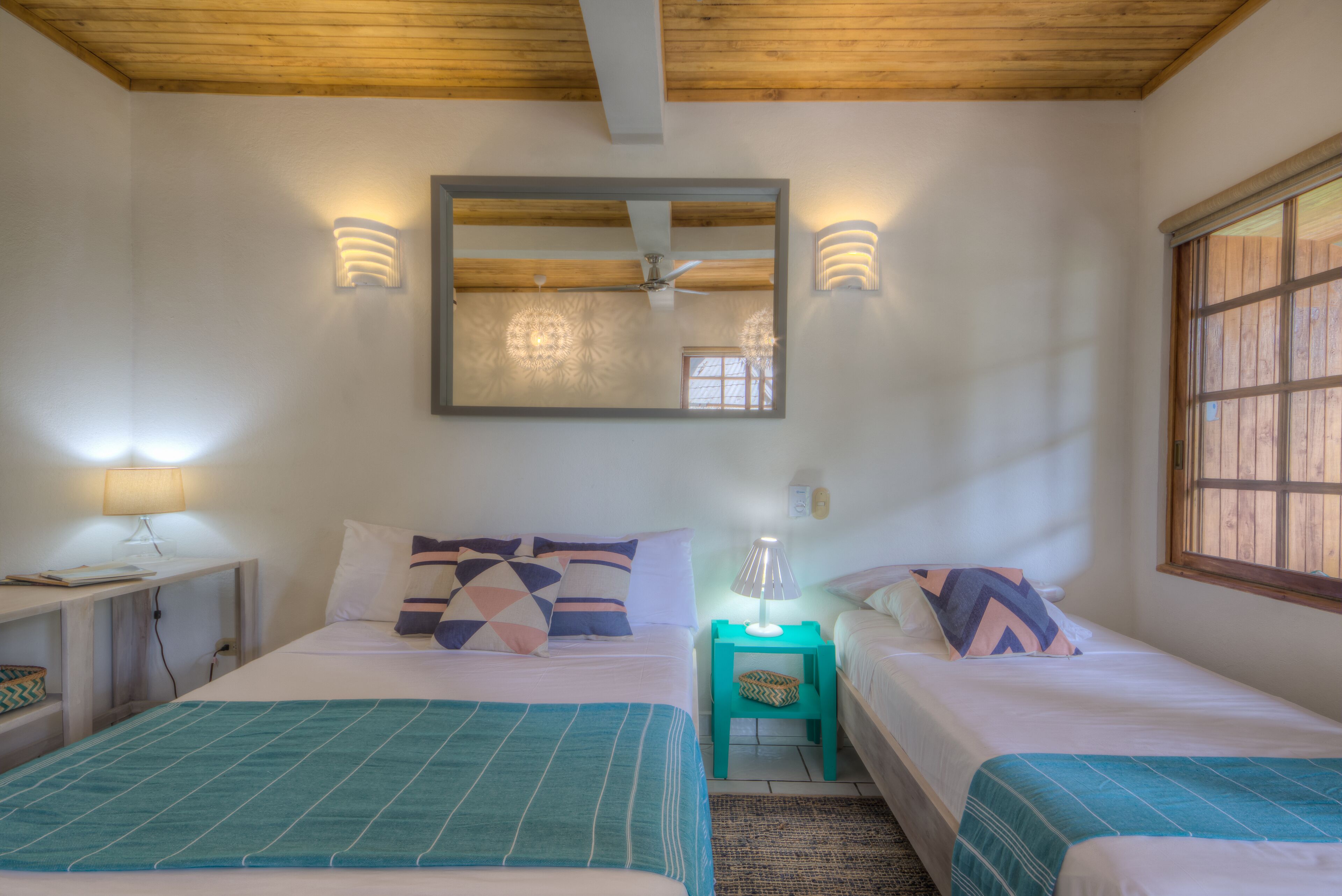 Ein Schlafzimmer mit zwei Betten, einem Deckenventilator und einem großen Spiegel.