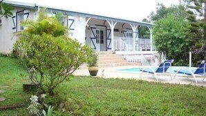 A two-story building with a covered porch, a swimming pool, and lounge chairs. - Quiet cottage in beautiful location on the edge of rainforest, (Unknown)