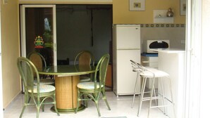 A compact kitchen with a refrigerator, a small bar area, and a dining table with four chairs. - Quiet cottage in beautiful location on the edge of rainforest, (Unknown)
