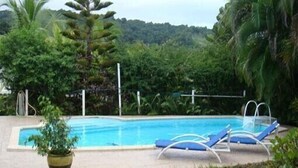 A swimming pool with lounge chairs and a potted plant. - Quiet cottage in beautiful location on the edge of rainforest, (Unknown)