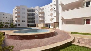 A modern apartment complex with a central courtyard featuring a swimming pool. - Apartment in Bouznika 4287 (Bouznika)