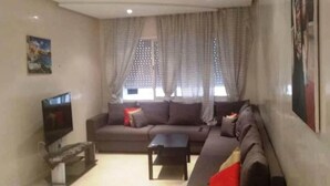 A living room with a sofa, a coffee table, a TV, and curtains. - Apartment in Bouznika 4287 (Bouznika)
