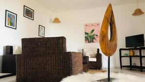 A living room with a wicker sofa, a round white rug, and a wooden sculpture. - Beachfront villa in Mdiq 4289 (Mdiq)
