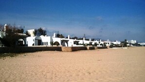 A sandy beach with white buildings in the background. - Beachfront villa in Mdiq 4289 (Mdiq)