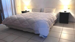 A bedroom with a large bed, two bedside tables, and a window with curtains. - Beachfront villa in Mdiq 4289 (Mdiq)