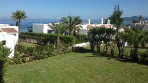 A coastal property with white buildings, a grassy lawn, and palm trees. - Beachfront villa in Mdiq 4289 (Mdiq)