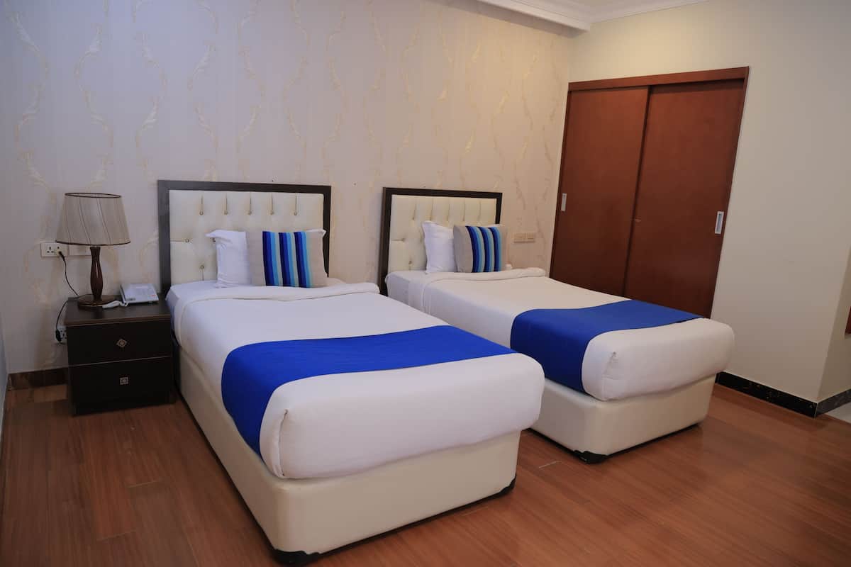 A hotel room with two beds, a nightstand, and a wardrobe.