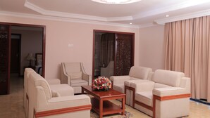 A living room with beige sofas, a wooden coffee table, and a chandelier. - Tolip Olympia Hotel (Addis Ababa)