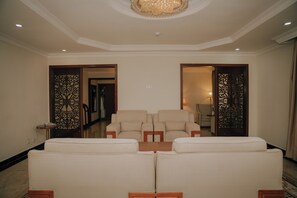 A spacious living area with a sofa set, a coffee table, and a chandelier. - Tolip Olympia Hotel (Addis Ababa)