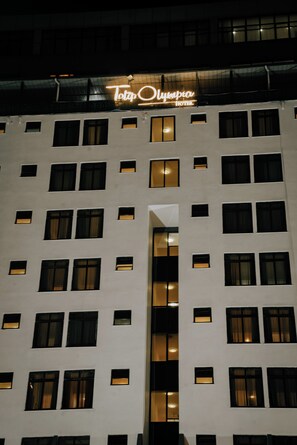 A hotel building with multiple windows and a neon sign above the entrance. - Tolip Olympia Hotel (Addis Ababa)