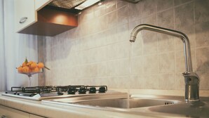 Eine Küche mit einem Gasherd, einem Spülbecken mit einem modernen Wasserhahn und einer Orangenschale auf der Arbeitsplatte.