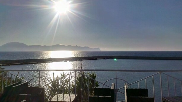 Ein Balkon mit Blick auf das Meer und die Berge.
