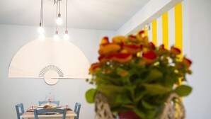 Ein Essbereich mit Tisch, Stühlen, einer Hängelampe und einem an der Wand befestigten Ventilator.