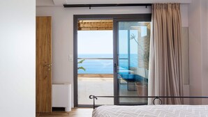 A bedroom with a bed, a sliding glass door leading to a balcony with a view of the sea. - Private swimming pool, amazing views, sleeps 6. (Rethymno)