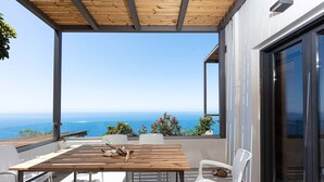 A wooden table and white chairs on a balcony with a view of the sea. - Private swimming pool, amazing views, sleeps 6. (Rethymno)