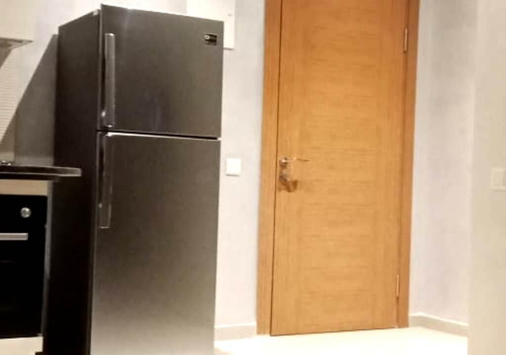 Eine Küche mit einem schwarzen Kühlschrank und einer Holztür.