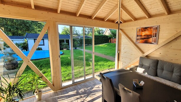A wooden interior with a sliding glass door leading to a backyard with a pool.