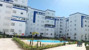 A modern building with multiple floors, a swimming pool, and a well-maintained garden area. - Beautiful apartment in Fal Azur 4388 (Bouznika)