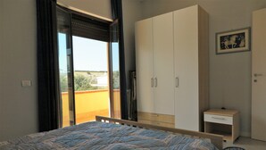 Une chambre avec un lit, une armoire, une petite table de chevet et une vue sur l’extérieur.