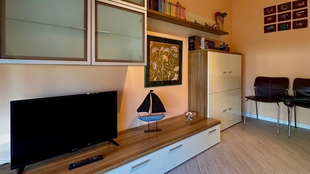 Un salon moderne avec un téléviseur à écran plat, une console en bois, une lampe décorative et une bibliothèque.
