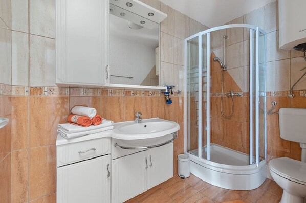 A modern bathroom with a curved shower enclosure, a sink, and a toilet.