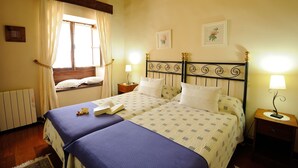 A double bed with a wooden headboard, two bedside tables with lamps, a window with curtains, and a radiator.