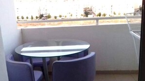 A balcony with a round glass table and two purple chairs. - Residence Islane Agadir 4282 (Agadir)
