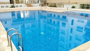 A swimming pool with a clear blue water surface, surrounded by a tiled deck and a metal ladder. - Residence Islane Agadir 4282 (Agadir)