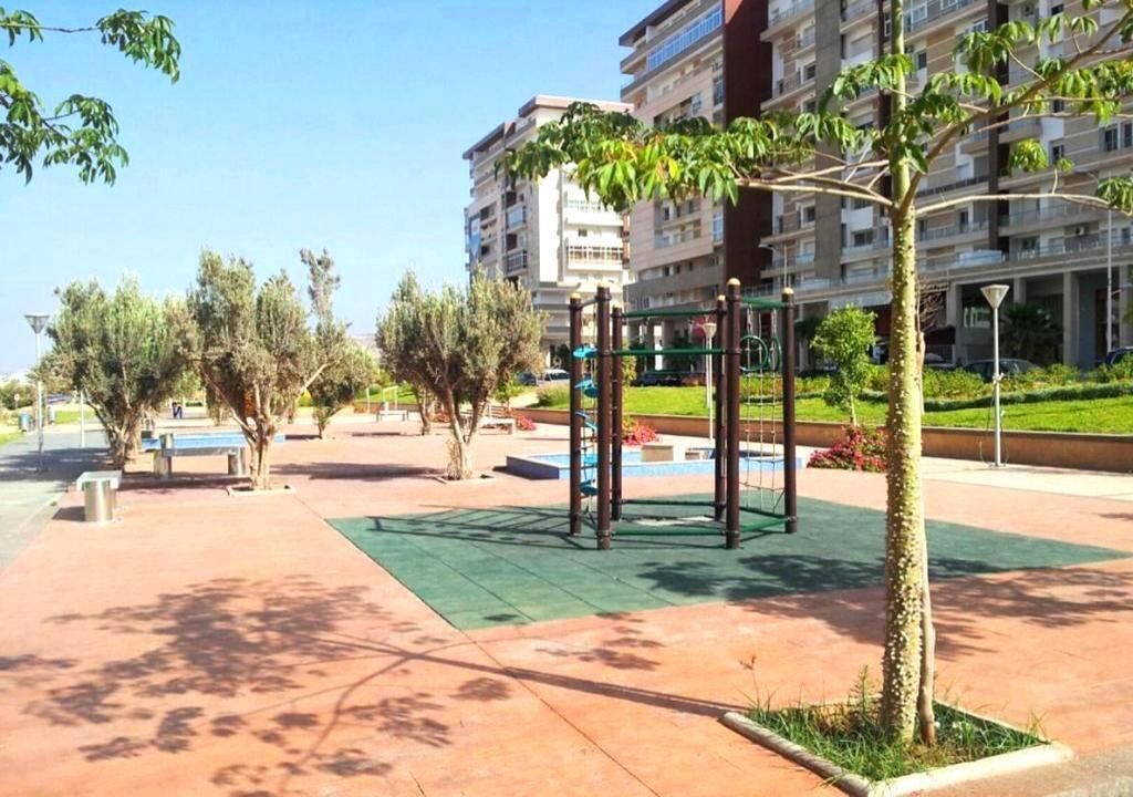 An outdoor area with a playground, benches, and trees.
