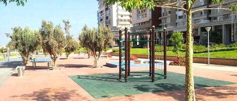 An outdoor area with a playground, benches, and trees.