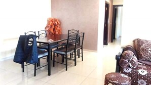 A dining area with a table and chairs, a patterned sofa, and a door in the background. - Apartment in Islane Agadir 4468 (Agadir)