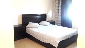 A single bed with a dark headboard, a white bedspread, and two pillows. - Apartment in Islane Agadir 4468 (Agadir)