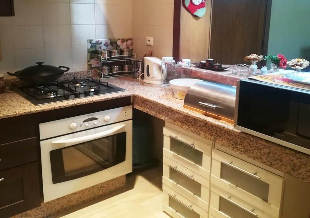 Eine Küche mit einem Gasherd, Backofen, einer Mikrowelle und verschiedenen Küchengeräten.