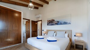 A bedroom with a large bed, wooden wardrobe, and a painting of a mountain landscape. - Finca Sa Pletassa, Villa with Private Pool (Horta, S' (Felanitx))