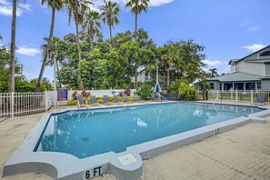 A rectangular swimming pool with a 6 FT depth marker, surrounded by a white fence, palm trees, and a building with a grey roof. - Siesta Bayside Villa: Water Views & Private Beach (Siesta Key)