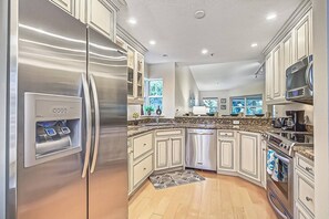 A modern kitchen with stainless steel appliances, white cabinetry, and a built-in dishwasher. - Siesta Bayside Villa: Water Views & Private Beach (Siesta Key)