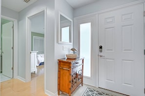A hallway with a wooden cabinet, a mirror, and a white door.