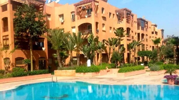 A hotel with a swimming pool surrounded by palm trees and a courtyard. - Beautiful apartment in Ricoflores Beach 4386 (Mohammedia)