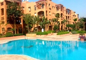 A hotel with a swimming pool surrounded by palm trees and a courtyard. - Beautiful apartment in Ricoflores Beach 4386 (Mohammedia)